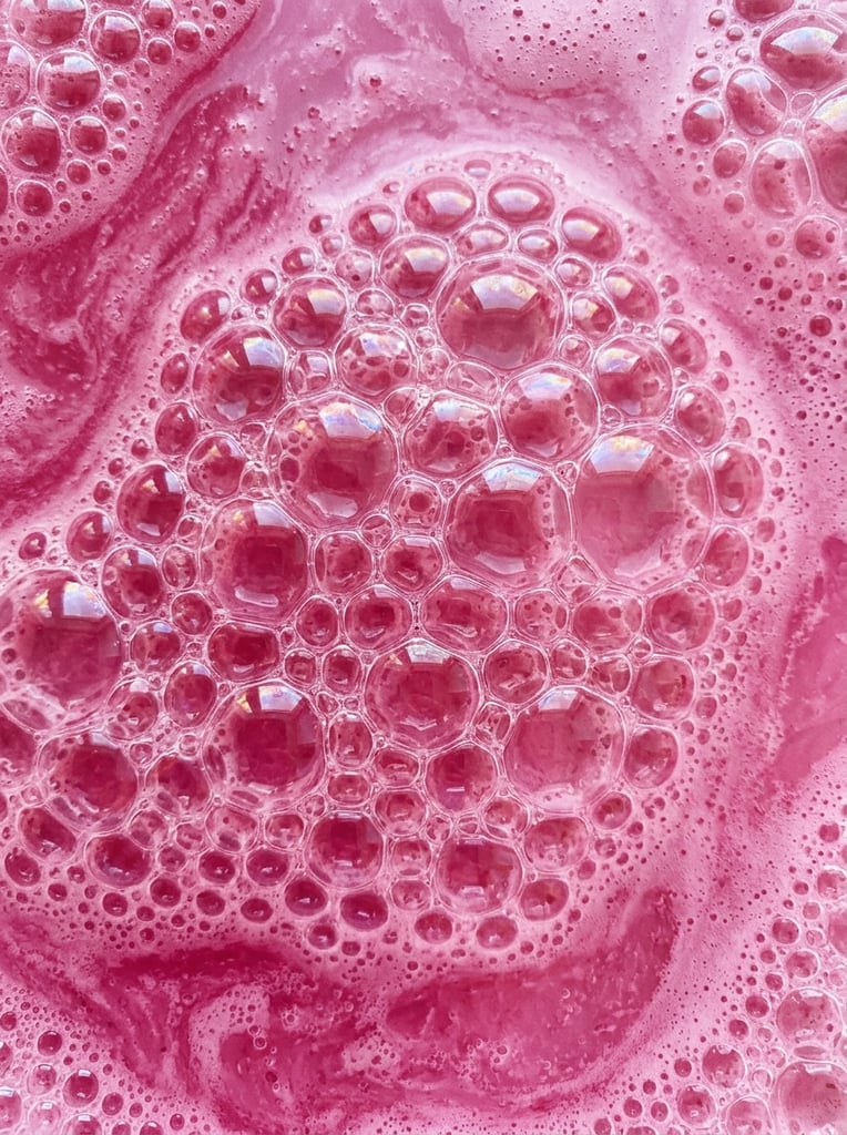 Texture of pink liquid with bubbles, pattern, background, top view, organic texture, seamless texture, rich colors, gradation of pink colors, macro photo, cluster of bubbles