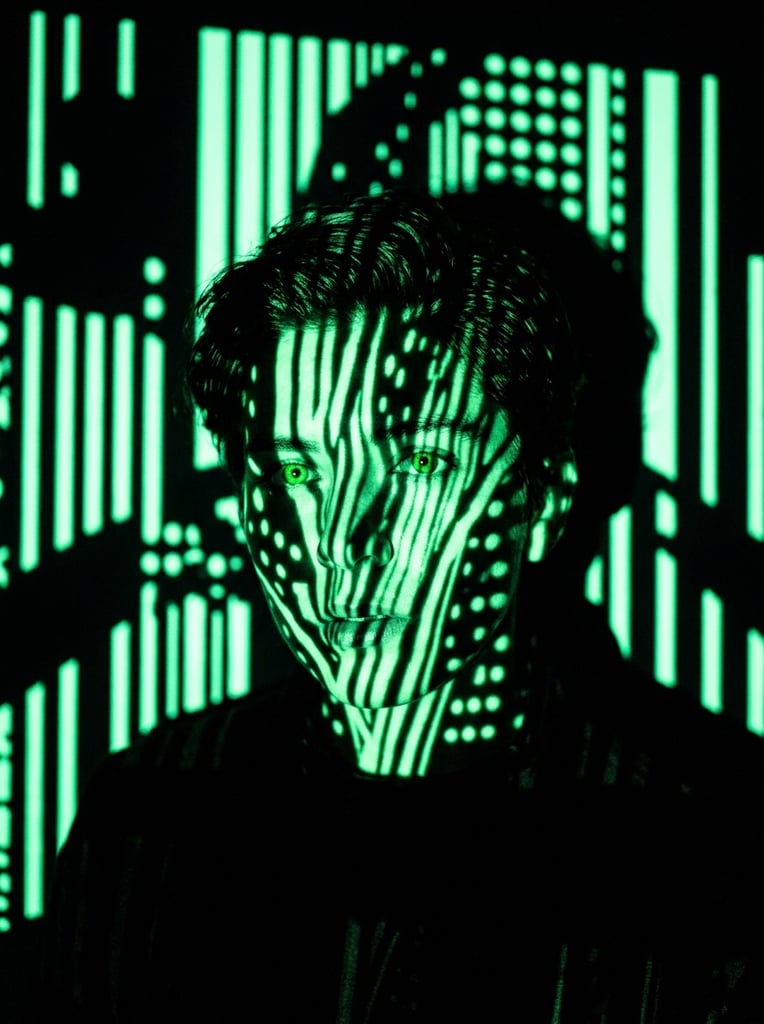 A human face rendered barely visible through an intense, high-contrast projection of glowing mint-green vertical lines and scattered spots. The facial structure is defined exclusively by stark gobo lighting, where the vivid neon green patterns wrap around the three-dimensional contours of the skin against an absolute pitch-black void. The striking monochromatic color palette consists solely of pure, deep black and luminous, saturated mint green. Harsh, directional light creates crisp, graphic transitions between the radiant green stripes and the solid black shadows. In the surrounding space, graphic light projections form sharp, bright green vertical bars and circular dots on a flat background plane, interrupted by stark, pitch-black silhouettes blocking the light. The composition relies entirely on dramatic neon light mapping to reveal the central subject, resulting in a surreal, highly graphic aesthetic with sharp focus on the luminous projected textures.