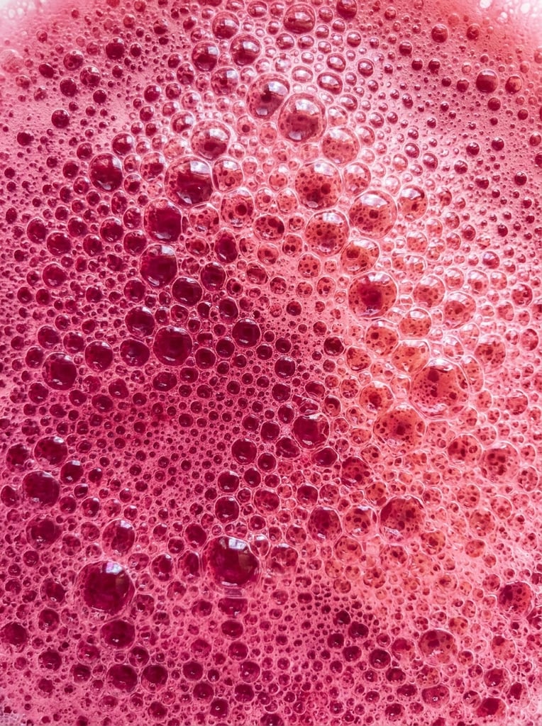Texture of pink liquid with bubbles, pattern, background, top view, organic texture, seamless texture, rich colors, gradation of pink colors, macro photo, cluster of bubbles