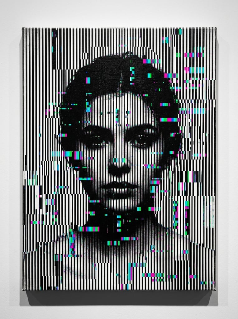 A shadowy human face emerges from a dense optical illusion of vertical black and white lines. The stark stripes are heavily fractured by digital noise and scattered rectangular RGB pixel glitches in cyan, magenta, and green. The varying density and fragmentation of the patterned lines form the contours of a person with dark hair and a neutral forward gaze. The artwork is presented as a flat canvas mounted on a stark white wall with a subtle drop shadow along its bottom edge.
